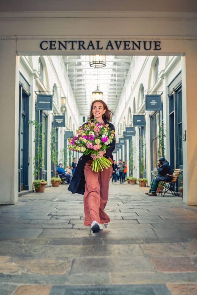 Cinefleur Amanda walking through street with bouquet in hand