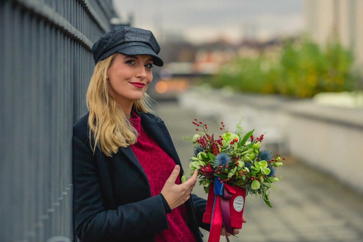 Woman holding flowers leaning against fence used for article videomarketing