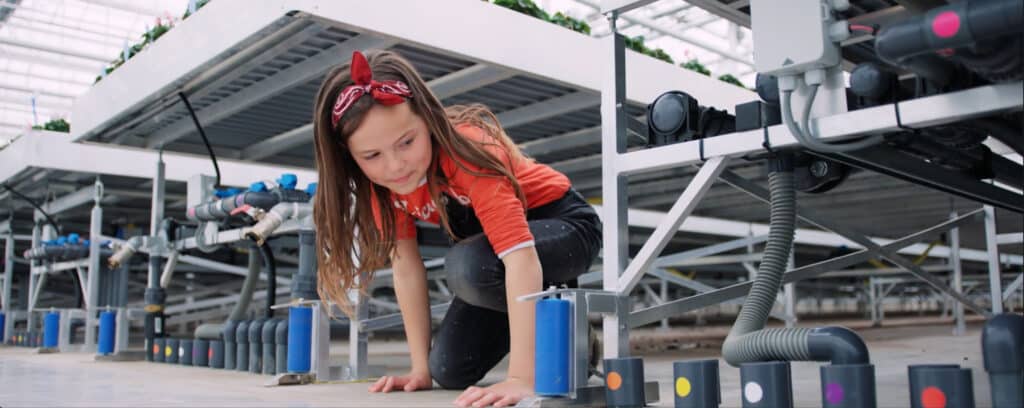 Girl looking at water system of greenhouse