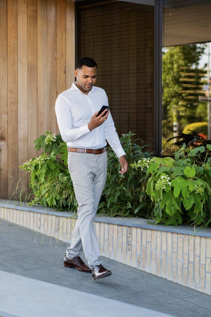 Man checking phone in front of office