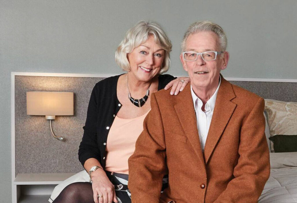 two people sitting next to each other on bed