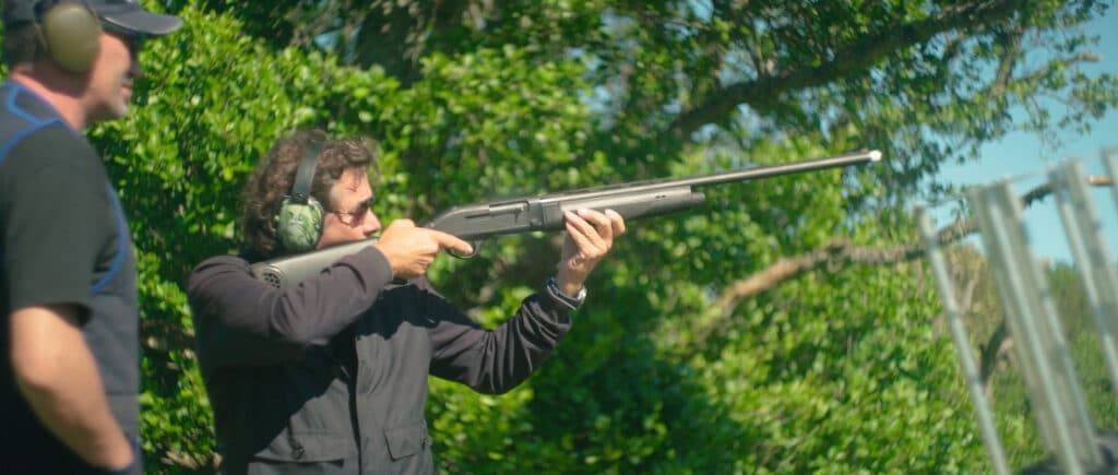 Man holding a rifle shooting clay targets